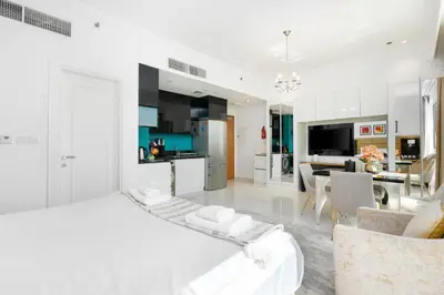 a white bedroom with a kitchen and a living room at Vacay Lettings - DAMAC Capital Bay Tower in Dubai