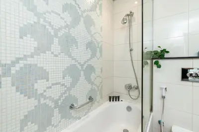 a bathroom with a shower and a bath tub with a glass door at Vacay Lettings - DAMAC Capital Bay Tower in Dubai