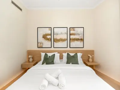 a bedroom with a white bed with four pictures on the wall at Royal Vista - Luxury 2BR Apartment at Burj Views Tower A - Downtown in Dubai