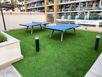 two ping pong tables on grass in front of a building at Burj Khalifa View Pool Gym 10 Min To Downtown in Dubai