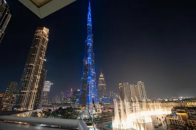 a tall building lit up in blue lights in a city at GuestReady - Charming stay with Burj Khalifa views in Dubai