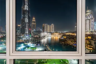 a window with a view of a city at night at GuestReady - Charming stay with Burj Khalifa views in Dubai