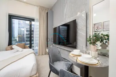 a bedroom with a bed and a table and a tv at Chic Studio in Azizi Riviera 46, Al Merkadh by Deluxe Holiday Homes in Dubai