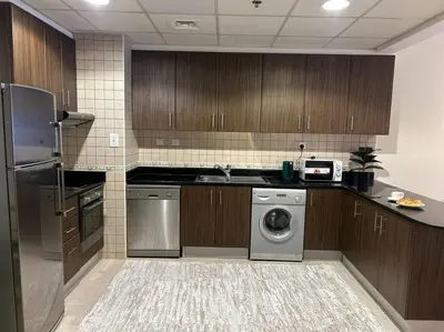 a kitchen with wooden cabinets and a washer and dryer at 1BHK in Dubai Marina near tram in Dubai
