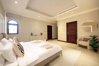 a white bedroom with a large bed and a chair at Cozy 4BR Maid Villa at Canal Cove Palm Jumeirah in Dubai