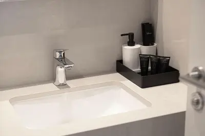 a white sink in a bathroom with a black holder at Dubai Mall Connected! AMAZING Burj Khalifa View! Excellent Pool & Gym Access! in Dubai