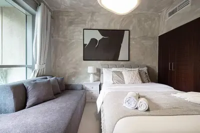 a bedroom with two beds and a couch at Stylish 1-BR Oasis Minutes from Burj & Dubai Mall in Dubai
