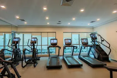 a gym with several tread machines in a room at Stylish 1-BR Oasis Minutes from Burj & Dubai Mall in Dubai