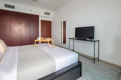 a bedroom with a bed with a table and a tv at Frank Porter - Time Place Tower in Dubai
