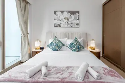 a bedroom with a large white bed with blue pillows at Near Burj Khalifa & Dubai Mall - 1BR in Grande Residence, Downtown - Allsopp & Allsopp in Dubai