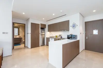 a kitchen with brown cabinets and a white counter top at Near Burj Khalifa & Dubai Mall - 1BR in Grande Residence, Downtown - Allsopp & Allsopp in Dubai