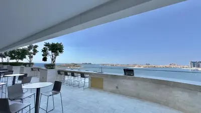 a balcony with tables and chairs and a view of the water at Guest Favorite 1BR Designer Apt with Beach Access by Vibel in Dubai