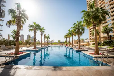 a swimming pool with palm trees in a resort at Quirky Studio Apartment in Damac Ghalia in Dubai