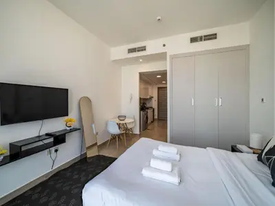 a bedroom with a large white bed with a flat screen tv at Brand New Premium Studio In JVC in Dubai