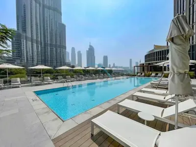 a swimming pool with lounge chairs and umbrellas on a building at Elegant 3BR at The Address Residences Dubai Opera, Downtown Dubai by Deluxe Holiday Homes in Dubai