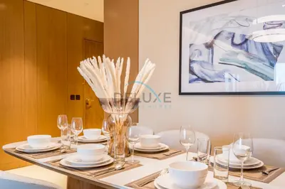 a table with plates and glasses and a vase with flowers at Elegant 3BR at The Address Residences Dubai Opera, Downtown Dubai by Deluxe Holiday Homes in Dubai