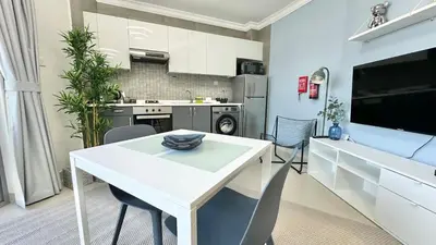 a kitchen with a white table and chairs in a room at Spacious Luxury Studio Near Mall of the Emirates with Pool Access in Dubai