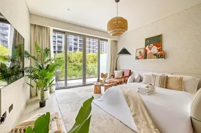 a bedroom with a large white bed and a living room at Spacious 1BR with Pool, Gym & Kids Play Area in Dubai