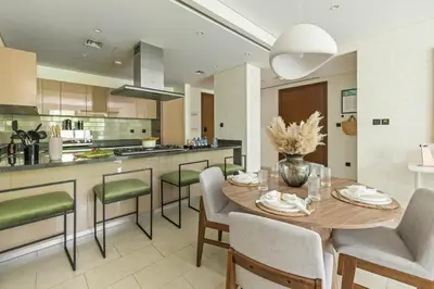 a kitchen with a wooden table and chairs in a kitchen at Spacious 1BR with Pool, Gym & Kids Play Area in Dubai
