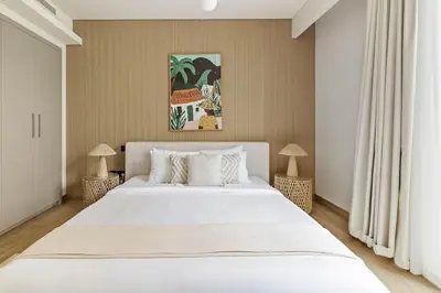 a bedroom with a large white bed and two lamps at Spacious 1BR with Pool, Gym & Kids Play Area in Dubai
