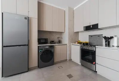 a kitchen with white cabinets and a washer and dryer at New Family Villa with PS5, Garden and Playroom in Dubai