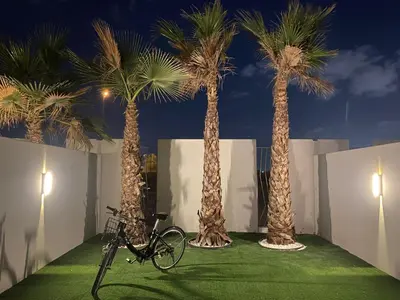 a bike parked between three palm trees at night at New Family Villa with PS5, Garden and Playroom in Dubai