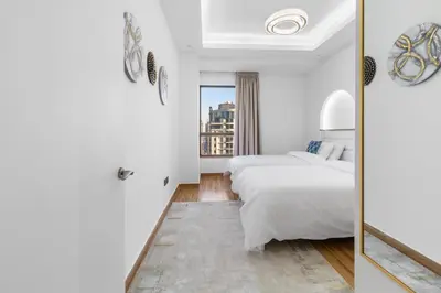 a white bedroom with a bed and a mirror at 2BR Marina View - Beach Access - Sleeps 8 in JBR in Dubai