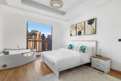 a white bedroom with a bath tub and a bed at 2BR Marina View - Beach Access - Sleeps 8 in JBR in Dubai