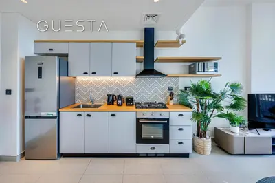 a kitchen with white cabinets and a stainless steel refrigerator at Collective Tower, Dubai Hills Estate in Dubai