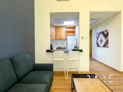 a living room with a couch and a kitchen at Rare Holiday Homes - Near Metro - Garden View - Mogul Cluster - Building# 204 - RG09 - Discovery Gardens in Dubai