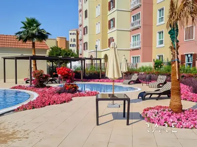 a hotel courtyard with a pool and a umbrella at Rare Holiday Homes - Near Metro - Garden View - Mogul Cluster - Building# 204 - RG09 - Discovery Gardens in Dubai