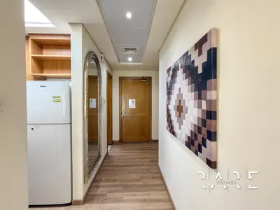a hallway with a refrigerator and a painting on the wall at Rare Holiday Homes - Near Metro - Garden View - Mogul Cluster - Building# 204 - RG09 - Discovery Gardens in Dubai