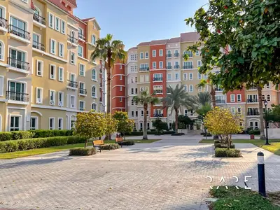 a park in front of a building with palm trees at Rare Holiday Homes - Near Metro - Garden View - Mogul Cluster - Building# 204 - RG09 - Discovery Gardens in Dubai