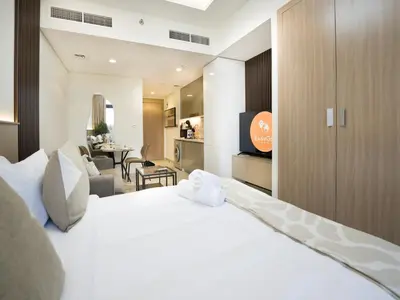 a bedroom with a white bed and a living room at EasyGo - Bright and Airy Studio in Azizi Riviera 9 in Dubai