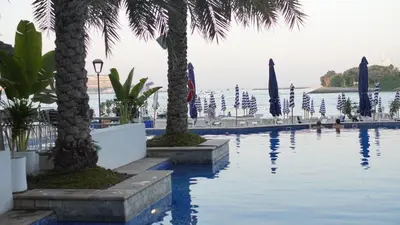 a swimming pool with palm trees and umbrellas at 2 Bedroom beach front apartment in Dubai