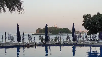 a swimming pool with blue umbrellas and chairs at 2 Bedroom beach front apartment in Dubai