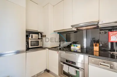 a kitchen with white cabinets and stainless steel appliances at Lovely Studio in The Address Residence Dubai Marina by Deluxe Holiday Homes in Dubai