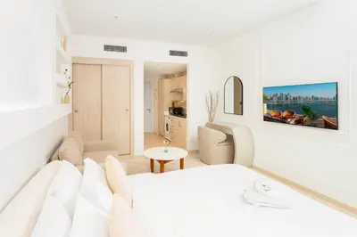a white bedroom with a bed and a living room at Apartment on Palm Jumeirah Beach Parking in Dubai