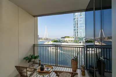a balcony with chairs and a view of the water at Cozy and Stunning Waterfront One Bed in Dubai