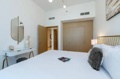 a bedroom with a white bed and a mirror at Cozy and Stunning Waterfront One Bed in Dubai