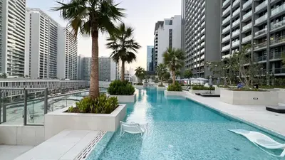 a large swimming pool with palm trees and buildings at Outstanding New Studio With 2 Double Beds,In Downtown in Dubai