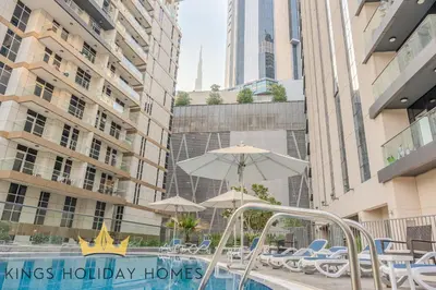 a swimming pool with umbrellas and chairs and buildings at Luxury 2 Apartments Dunya tower Burj Khalifa St in Dubai