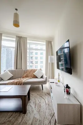a white living room with a couch and a tv at 2BR Luxury Apartment in Downtown Opposite Mall and Fountain Entrance in Dubai
