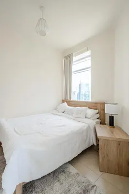 a white bedroom with a large bed and a window at 2BR Luxury Apartment in Downtown Opposite Mall and Fountain Entrance in Dubai