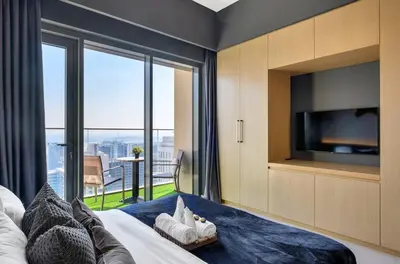 a bedroom with a bed with a tv and a balcony at Urban Zen Sky Suite 1BR - Dubai Mall Access by Maxx Value homes in Dubai