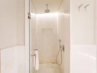 a white bathroom with a shower with a glass door at SettlerHomes - Elegant Palm Tower Stay with the Sea View in Dubai