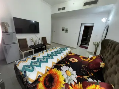 a living room with a couch and a bed with flowers on it at Bedroom with attach bath and balcony in Marina Dubai in Dubai