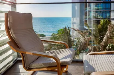 a rocking chair sitting on a balcony overlooking the ocean at Bluewaters Sea View 2BR Pool & Gym & Beachfront in Dubai