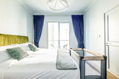 a bedroom with a bed with blue curtains and a window at Unique JBR Gem - Full Sea View - Designer's Choice - 5 min walk from JBR Beach in Dubai