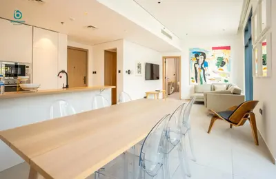 a kitchen and living room with a large wooden table at Blue Breeze - Elegant 1BR with Private Jacuzzi & Terrace in JVC in Dubai
